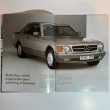 Open brochure showing a Mercedes-Benz 560 SEC car on a gray background